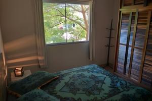 a bedroom with a bed and a window at Residencial Flamboyant in Garopaba