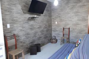 a bedroom with two chairs and a tv on a brick wall at Residencial Flamboyant in Garopaba