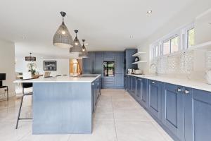 a kitchen with blue cabinets and a large island at Mayrose House - 6BR 4BATH Luxe Spacious Retreat in Takeley