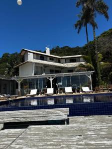 a house with a swimming pool with a bench in front of it at Pousada Ponta da Vigia in Penha
