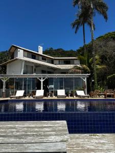 a house with a swimming pool in front of a house at Pousada Ponta da Vigia in Penha