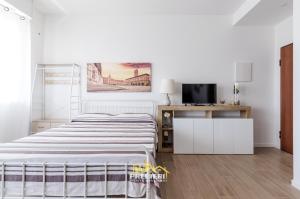 ein weißes Schlafzimmer mit einem Bett und einem Fernseher in der Unterkunft Borgo Panigale - near the Airport - Polleggio Home in Bologna
