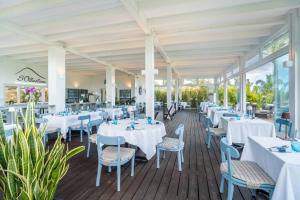a dining room with white tables and chairs at Cala Sinzias Resort in Castiadas
