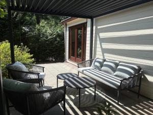 a patio with a couch and two chairs and a table at Het Bosgeluk in Voorthuizen