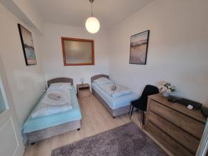 two beds in a room with a desk and a chair at Ida Apartman in Miskolc
