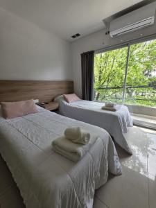 two beds in a room with a window at Aparts Magallanes in Pilar
