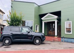 a black suv parked in front of a green house at Vacation house ITER in Hakodate