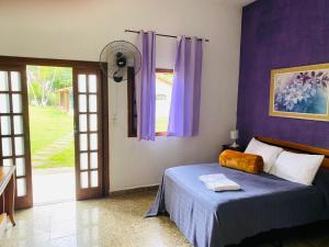 a bedroom with a bed with purple walls and a window at Pousada Maria Laura in Guararema