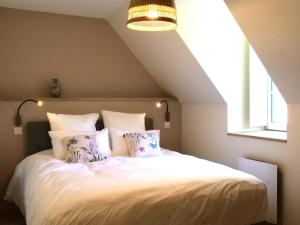 un dormitorio con una cama con sábanas y almohadas blancas en A l'abri des marées - Maison de charme dans le parc du Domaine du Cloitre, en Pléneuf-Val-André