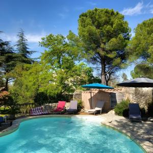 a swimming pool with chairs and umbrellas at Les Althéas - Gîte En Ardèche in Chandolas