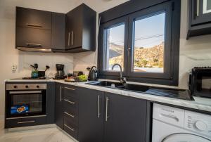 a kitchen with black cabinets and a sink and a window at Luna in Kalymnos