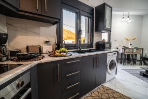 a kitchen with black cabinets and a sink and a dishwasher at Luna in Kalymnos