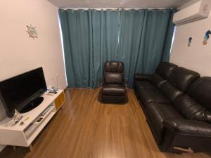 ein Wohnzimmer mit Ledercouch und Fernseher in der Unterkunft Habitaciones baratas, Cerca de la Plaza de Toros in Alicante