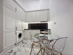 a white kitchen with a glass table and chairs at Cris & Ema Luxury Downtown Apartment in Arad +1 photo