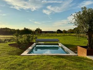 a pool with a bench in the middle of a field at Le Logis du Chêne in Vendeuvre-du-Poitou