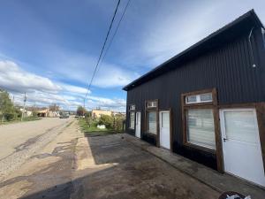 a black building with two garage doors next to a street at ABBA Departamento turistico in Trevelin