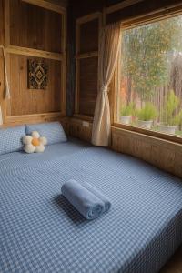 Bett mit Kissen vor einem Fenster in der Unterkunft Ri's Garden Homestay - Nhà gỗ bên sườn đồi in Da Thien