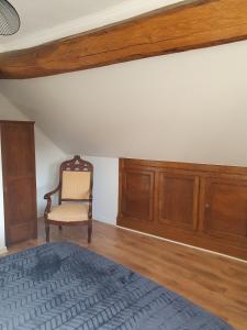 a bedroom with a chair and a bed and wooden cabinets at Maison de campagne in Aignay-le-Duc
