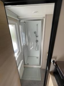 a walk in shower in a bathroom with a mirror at Cosy Mobil-Home climatisé in Aureilhan