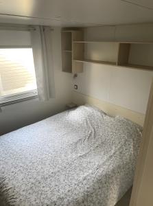 a bedroom with a bed and a window at Charmant Mobil-Home climatisé in Aureilhan
