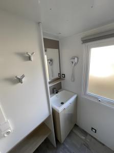 a white bathroom with a sink and a window at Charmant Mobil-Home climatisé in Aureilhan +19 photos