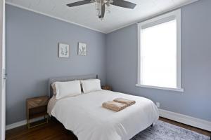 a bedroom with a white bed with a ceiling fan at 20 min to NYC, Newly Renovated, Private Driveway in Little Ferry