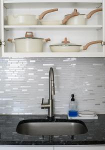 a kitchen counter with a sink and shelves with dishes at 20 min to NYC, Newly Renovated, Private Driveway in Little Ferry