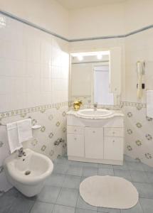 bagno bianco con lavandino e servizi igienici di Albergo Villa Hibiscus a Ischia