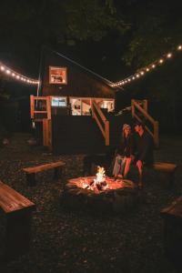 two people sitting around a fire in front of a cabin at NWPADS-Verlot River Cabin - Hot Tub-Firepit-Beach in Granite Falls
