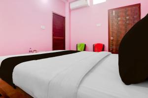 Un dormitorio con una cama blanca y dos sillas de colores. en SPOT ON Hotel Chandi, en Bihār Sharīf