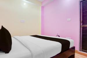 1 dormitorio con 1 cama con paredes blancas y moradas en SPOT ON Hotel Chandi, en Bihār Sharīf