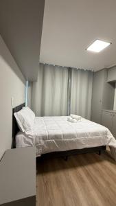 a bedroom with a large bed with white sheets at Residencial Roberto Luiz Chiodi in Campos Novos