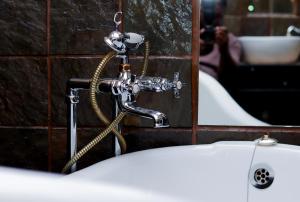 a bathroom sink with a hose attached to a wall at GBL Reine Chateau in Polokwane