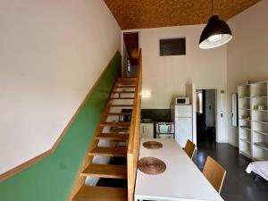 ein Raum mit einer Treppe mit einem Tisch und einer Küche in der Unterkunft Gîte de la Gare 3 in Voulaines