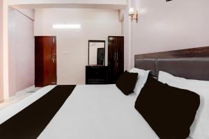 a bedroom with a large white bed with black pillows at Hotel O RR Palace Hotel & Banquet in Bhauli