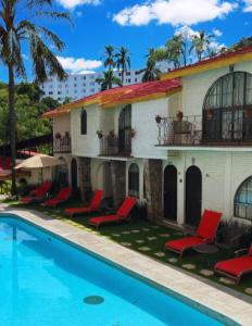 クエルナバカにあるHotel Ilebal Cuernavaca Centro - lugar con encanto!の建物の隣にプールと赤い椅子があるホテル