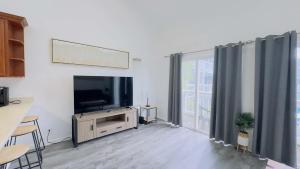 a living room with a flat screen tv and curtains at Lovely 2 bedroom condo with pool J3 in Little River