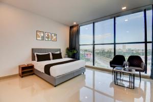 a bedroom with a bed and two chairs and large windows at Hotel O Lotus Inn in Chinchiwad +45 photos