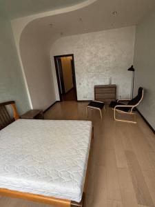 a bedroom with a white bed and a chair at Квартира в центре in Dnipro