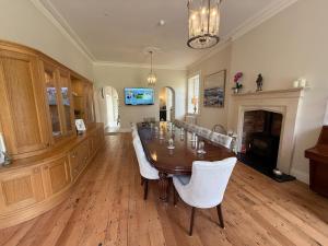 a dining room with a wooden table and white chairs at Meathpark Country House in Coleraine