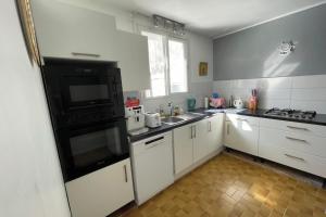 a kitchen with white cabinets and a black appliance at Villa Kaz a Ramon in Port-Louis