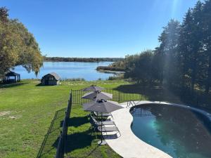 a pool with chairs and umbrellas next to a lake at Tackle Box Retreat in Deseronto