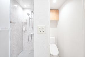 a white bathroom with a shower and a toilet at Unite Stay Gyotoku in Tokyo