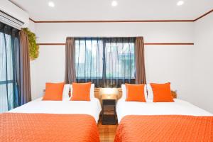 two beds with orange pillows in a room with a window at Unite Stay Gyotoku in Tokyo