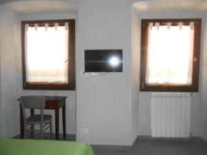 um quarto com uma televisão numa parede com duas janelas em Casa della Valle em Trisobbio