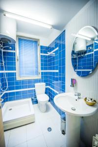 a blue tiled bathroom with a sink and a toilet at Luani A Hotel in Shkodër