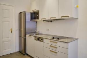a kitchen with white cabinets and a stainless steel refrigerator at Schlossquadrat Apartment 17 in Vienna