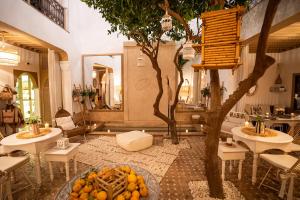 a room with two tables and a tree in it at Riad Les Orangers D'alilia in Marrakech