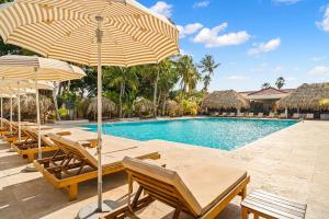 a pool with chairs and umbrellas next to a resort at Livingstone Jan Thiel Resort in Willemstad +31 photos