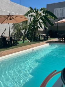 a swimming pool with an umbrella and tables and chairs at Espaço Varanda in Sao Paulo